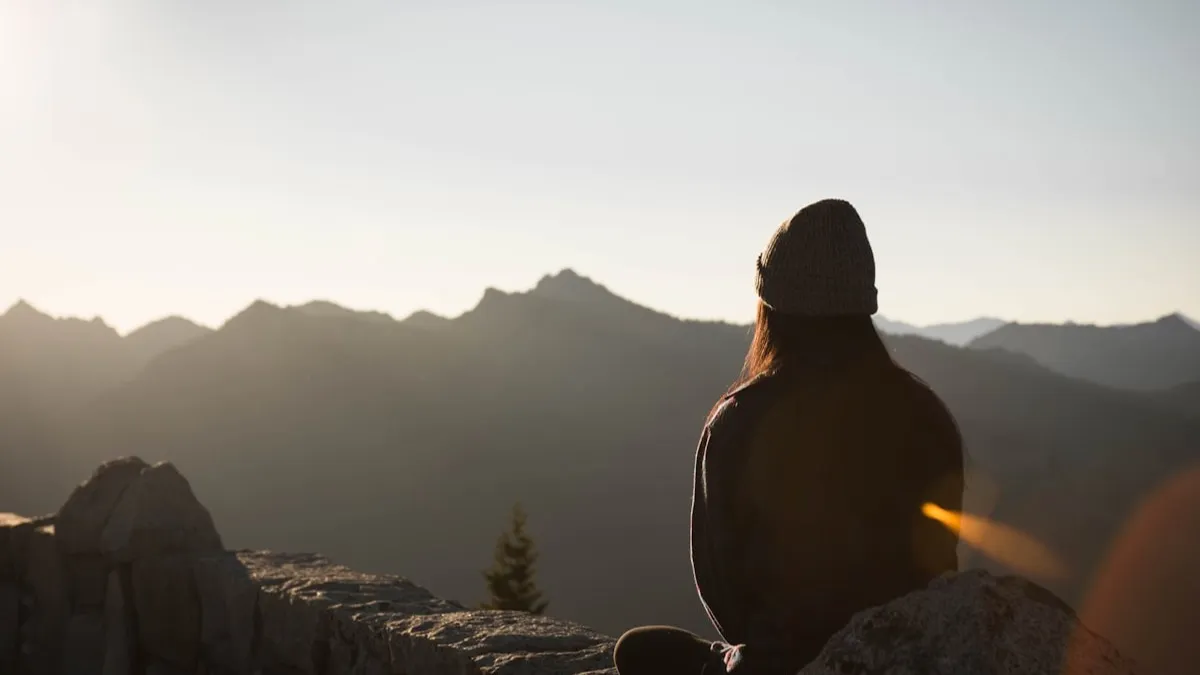 Mujer contemplativa mirando el horizonte al atardecer
